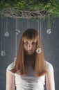 Portrait of young European female with crystal balls and christmas wreath, looking at camera with serious expression.