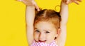 Portrait of young excited shocked crazy smiling baby girl holding hands isolated on yellow background Royalty Free Stock Photo