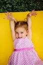 Portrait of young excited shocked crazy smiling baby girl holding hands isolated on yellow background Royalty Free Stock Photo