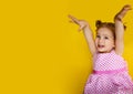 Portrait of young excited shocked crazy smiling baby girl holding hands isolated on yellow background Royalty Free Stock Photo