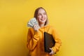 portrait of young exciting smiling pretty woman holding a stack of money dollar bills and laptop. Teenager Girl dreaming Royalty Free Stock Photo