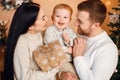 Brunette mother, father and little son standing near Christmas tree and hugging Royalty Free Stock Photo