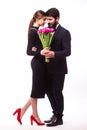 Portrait of young family couple in love with bouquet of lila tulips posing dressed in classic clothes on white backround.