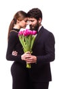 Portrait of young family couple in love with bouquet of lila tulips posing dressed in classic clothes on white backround.