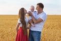 Portrait of young family in field background. Mom dad and baby on outsides. Happy family