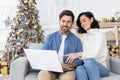 Portrait of a young family, a married couple, a man and a woman sitting at home on New Year's holidays doing online Royalty Free Stock Photo