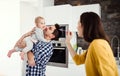 A young family at home, a man holding a baby and a woman feeding her. Royalty Free Stock Photo