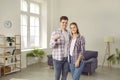 Portrait of a happy young family with keys standing in the living room in their new house Royalty Free Stock Photo