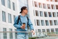 Portrait young fashionable man in casual clothes with coffee and sunglasses background of a white office building Royalty Free Stock Photo