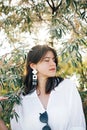 Portrait of young fashionable woman with modern earrings posing in  green olive branches in soft evening light, stylish boho girl Royalty Free Stock Photo