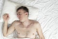 Portrait of young fast-sleeping man, top view. Sound sleep. Guy sleeps on white cotton bed linen