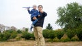 Portrait of young father holding his little son and teaching throwing toy airplane at park Royalty Free Stock Photo