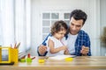 Portrait of young father teaching his cute little daughters\' study. Excited smiling small child girl enjoying learning with Royalty Free Stock Photo