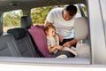 Portrait of young father wearing white t shirt securing cute baby with funny ponytail in the pink car seat in his car, children