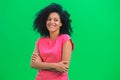 Portrait of young female African American flirtatious smiling. Black woman with curly hair in pink tshirt poses on green