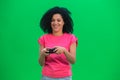 Portrait of young female African American playing a video game using a wireless controller. Black woman with curly hair Royalty Free Stock Photo