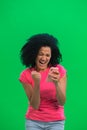 Portrait of young female African American is texting on phone and rejoice good news. Black woman with curly hair in pink