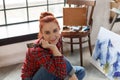 Portrait of a young female artist painting. Smiling girl sitting on the floor in art studio and looking at the camera Royalty Free Stock Photo