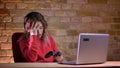 Portrait of young female blogger in red hoodie playing video game using joystick and failing with disgrace on bricken