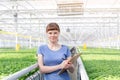 Portrait of young female botanist standing with clipboard in plant nursery