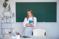 Portrait of young female college student studying in classroom on class with blackboard background. Royalty Free Stock Photo