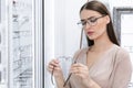 Portrait of young female customer choosing spectacles Royalty Free Stock Photo