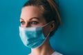 Portrait of young female doctor in medical mask and white gown on blue background. Royalty Free Stock Photo