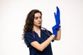 Portrait of young female doctor posing on white background, putting gloves on hands Royalty Free Stock Photo