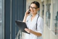 Portrait of young female doctor standing in hospital corridor. Caucasian woman working in nursing home. Royalty Free Stock Photo