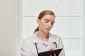 Portrait of a young female doctor in a white medical coat, writes in clipboard. Royalty Free Stock Photo