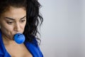 Portrait of young female executive dressed in blue and holding a blue balloon in her mouth with a sad face drawn on the blue