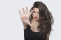 Portrait of a young female gesturing stop sign over gray background