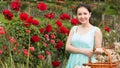 Portrait of young female holding a basket near roses in outdoors Royalty Free Stock Photo