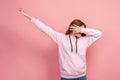 Portrait of young female in hoodie raising hands in dab dance pose, celebrating success, showing gesture of triumph, popular