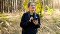 Portrait of young female journalist walking in forest with camera and looking for photography scenarios Royalty Free Stock Photo