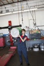 Portrait of a young female mechanic carrying oil drum on shoulder in auto repair garage