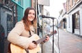 Portrait Of Young Female Musician Busking Playing Acoustic Guitar And Singing Outdoors In Street Royalty Free Stock Photo