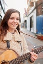 Portrait Of Young Female Musician Busking Playing Acoustic Guitar And Singing Outdoors In Street Royalty Free Stock Photo