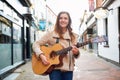 Portrait Of Young Female Musician Busking Playing Acoustic Guitar And Singing Outdoors In Street Royalty Free Stock Photo