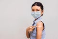 Portrait of a young female pointing plaster on arm after getting a vaccine. standing on white