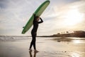 Portrait of young female surfer walking with surfboard at beach on sunset Royalty Free Stock Photo