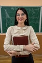 portrait of young female teacher against blackboard with math formula in classroom Royalty Free Stock Photo