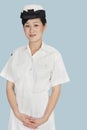 Portrait of a young female US Navy officer standing with hands clasped over light blue background