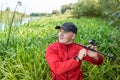 Portrait of a young fisherman in a thicket of reeds with a spinning rod