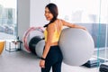 Portrait of young fit Asian woman holding exercise swiss ball and smiling at camera. Lively female fitness model image Royalty Free Stock Photo