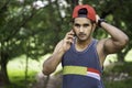 Portrait of Young fit Caucasian man with muscular body using smartphone outdoors on sunny summer day