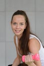 Portrait of young fitness sporty woman in sportswear sitting on fit ball and exercise with dumbbell on gray colour background. Royalty Free Stock Photo