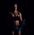 Portrait of a young fitness woman in sportswear doing workout with dumbbells on black background. Tanned athletic girl. Royalty Free Stock Photo