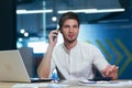 Portrait of young freelancer, businessman working in the office talking on the phone smiling and looking at camera Royalty Free Stock Photo