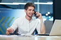 Portrait of young freelancer, businessman working in the office talking on the phone smiling and looking at camera Royalty Free Stock Photo